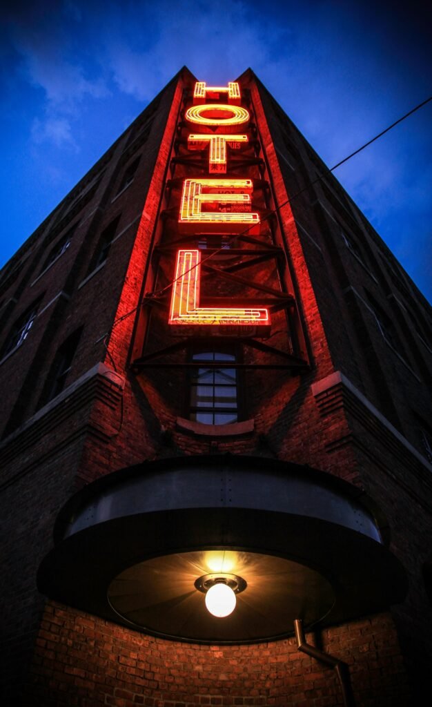 Hotelet Eye-catching low angle shot of a neon hotel sign illuminating a brick building facade at dusk.